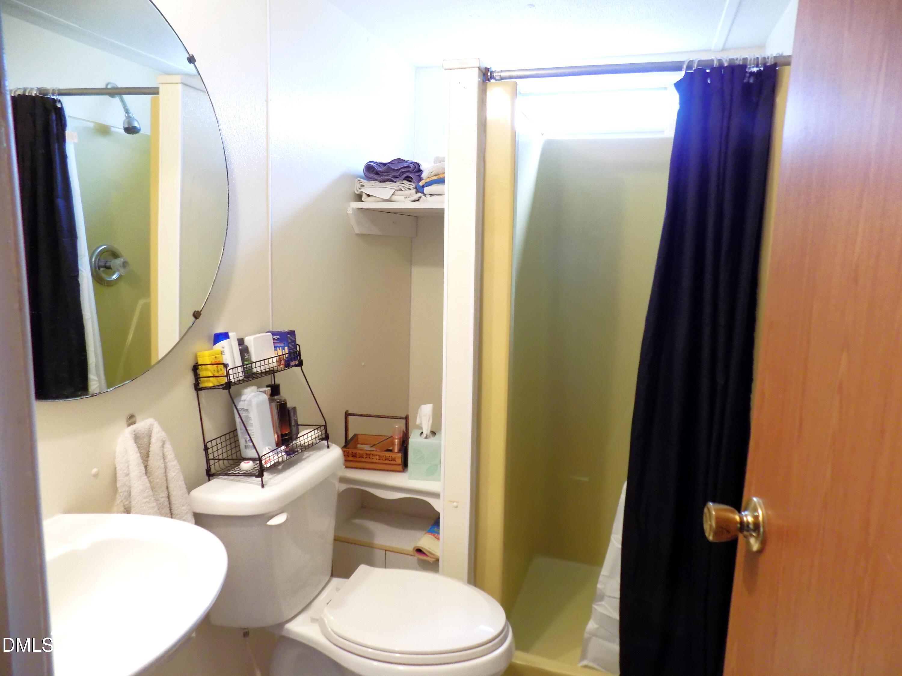 15 Full Circle Spring Hope, NC 27882 - Photo 38 of 51 a white toilet sitting next to a bathroom sink and a mirror