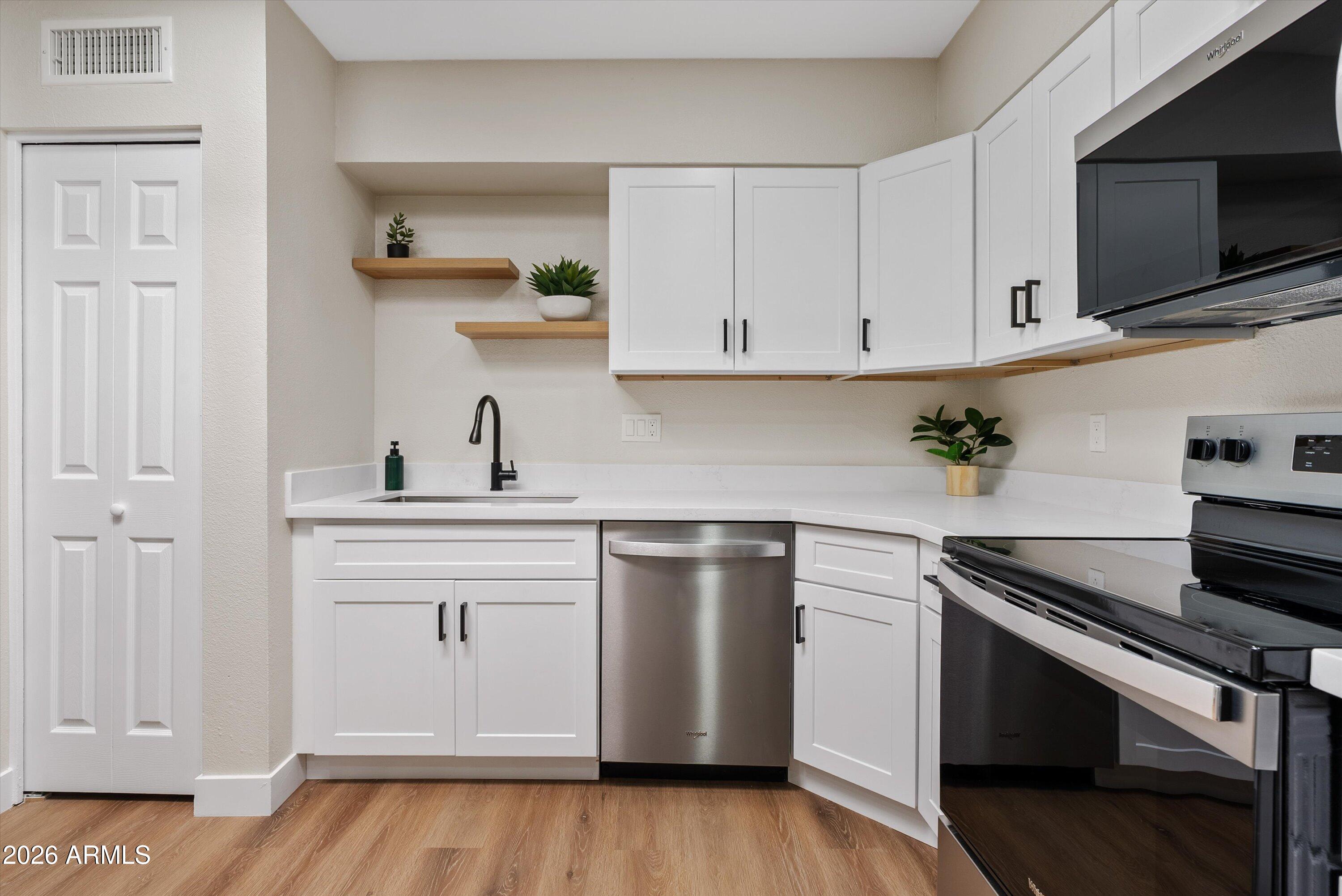 720 South Dobson Road, Unit 55 Mesa, AZ 85202 - Photo 11 of 33 a kitchen with white cabinets stainless steel appliances and wooden floor