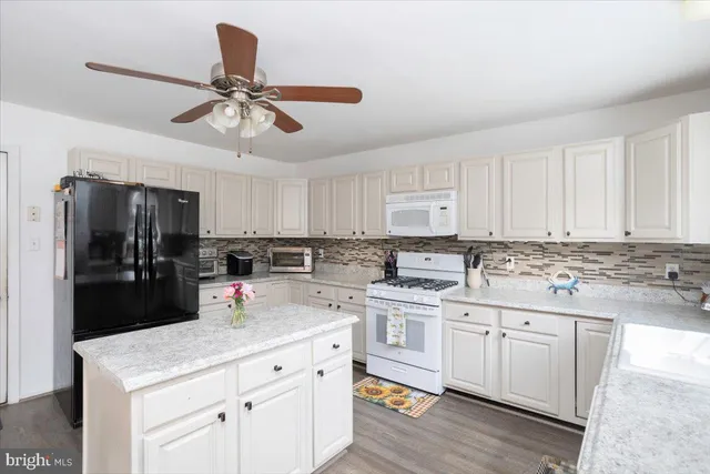 a kitchen with a sink dishwasher and white cabinets with wooden floor