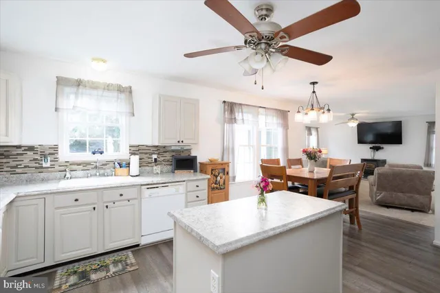 a open kitchen with stainless steel appliances granite countertop a sink dishwasher and white cabinets with wooden floor