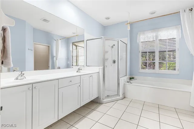 a spacious bathroom with a double vanity sink a mirror a bathtub and next to a window