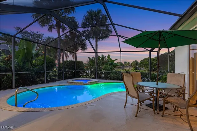 a view of a swimming pool with a table and chairs under an umbrella