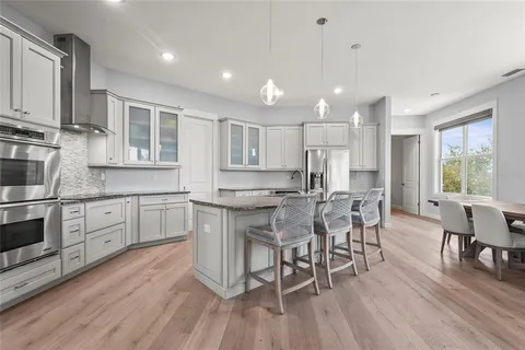 a kitchen with kitchen island granite countertop a stove top oven a sink a dining table and chairs with wooden floor