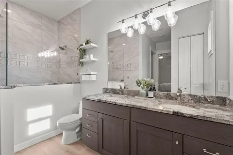 a bathroom with a granite countertop toilet sink and mirror