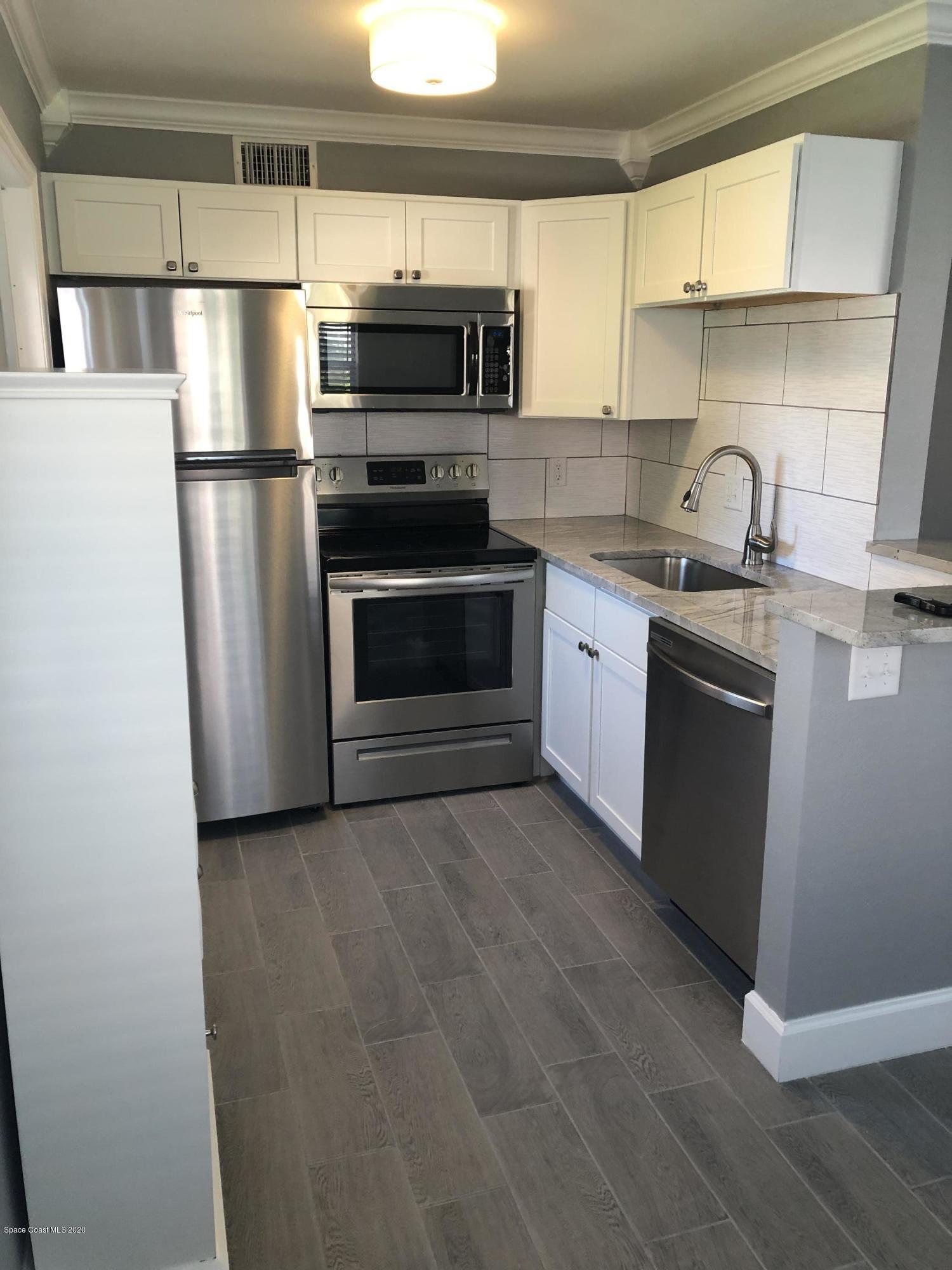 420 Monroe Avenue, Unit 101 Cape Canaveral, FL 32920 - Photo 5 of 35 a kitchen with a sink stove and refrigerator