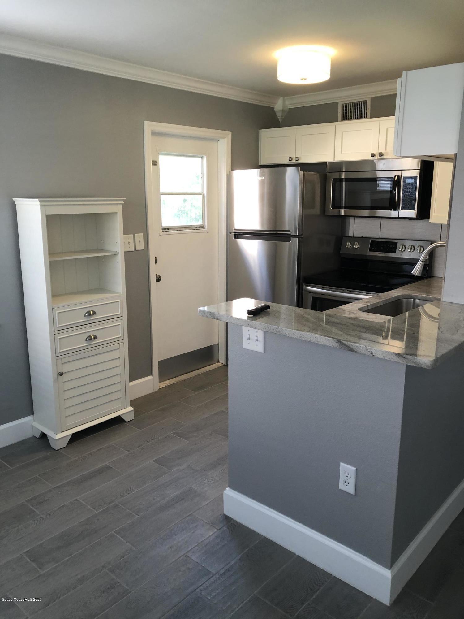 420 Monroe Avenue, Unit 101 Cape Canaveral, FL 32920 - Photo 6 of 35 a kitchen with kitchen island a refrigerator sink and stove
