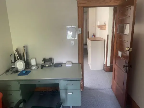 an empty room with a chair and windows