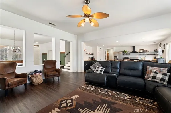 a living room with furniture kitchen view and a chandelier