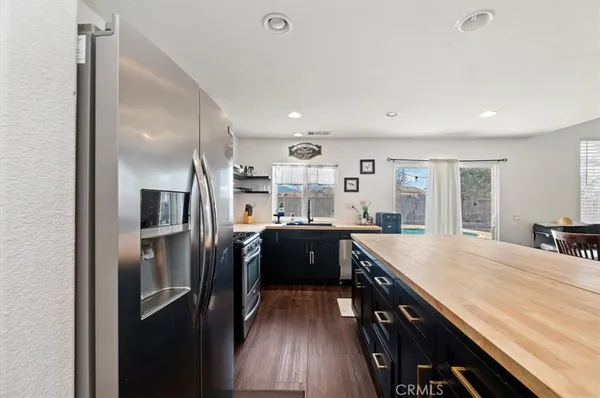 a kitchen with stainless steel appliances granite countertop a refrigerator a stove and a sink with wooden floor