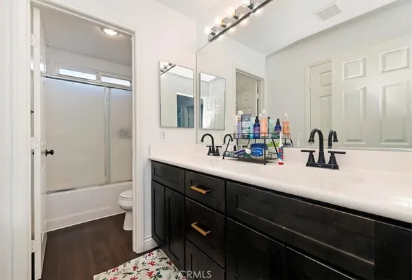 a bathroom with a double vanity sink a mirror and a toilet