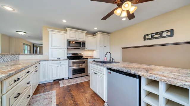 a kitchen with kitchen island granite countertop appliances cabinets and a sink