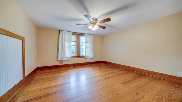 an empty room with wooden floor and ceiling fan