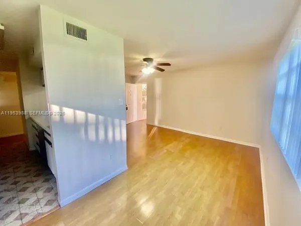 a view of an empty room with wooden floor and a window
