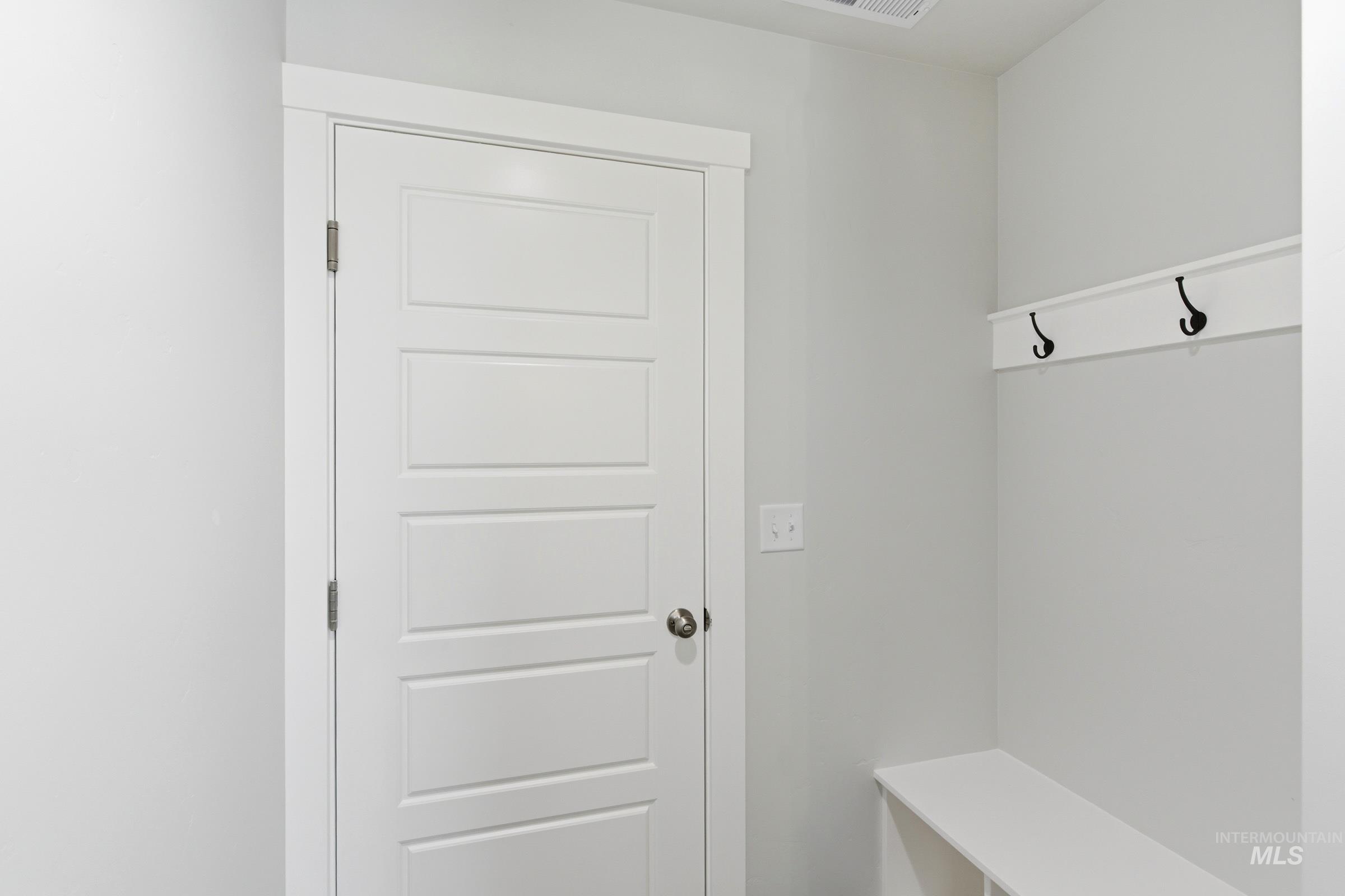 12829 Decatur Street Nampa, ID 83651 - Photo 17 of 33 Entryway mudroom featuring a white paneled door, built-in bench seating, wall-mounted coat hooks, light gray wall paint, and white trim