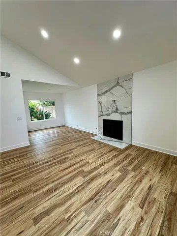 an empty room with a fireplace and wooden floor