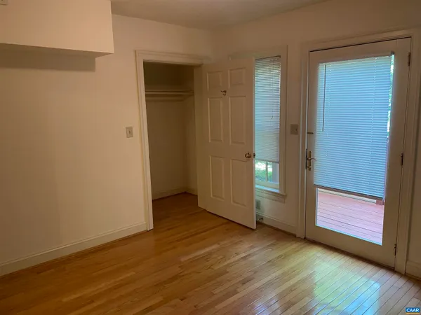 a view of an empty room with wooden floor and closet