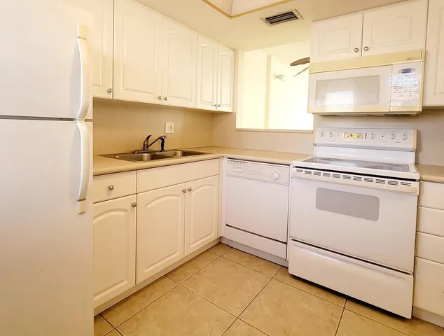 a kitchen with granite countertop white cabinets sink and white appliances