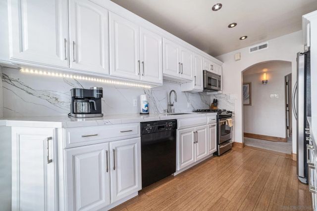 a kitchen with white cabinets and black appliances