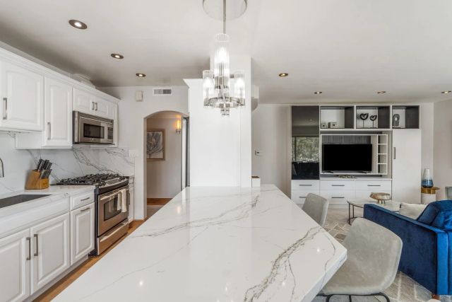 a kitchen with stainless steel appliances granite countertop a stove top oven a sink dishwasher a dining table and chairs with wooden floor