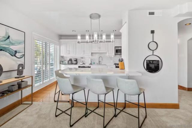 a dining room filled chandelier and kitchen view