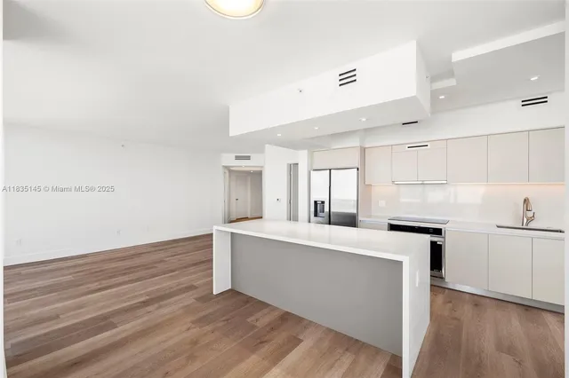 a kitchen with cabinets wooden floor and stainless steel appliances