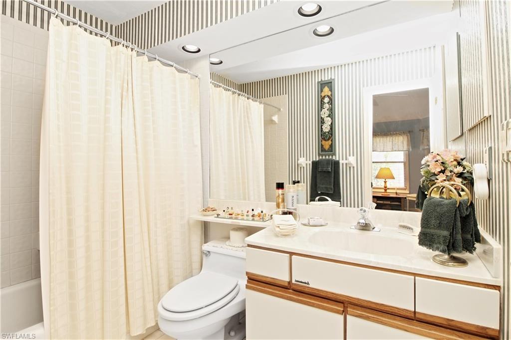 4028 Crayton Road, Unit C3 Naples, FL 34103 - Photo 13 of 32 a bathroom with a sink a toilet and shower curtain