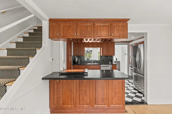 a kitchen with stainless steel appliances granite countertop a refrigerator a stove and a sink with wooden floors