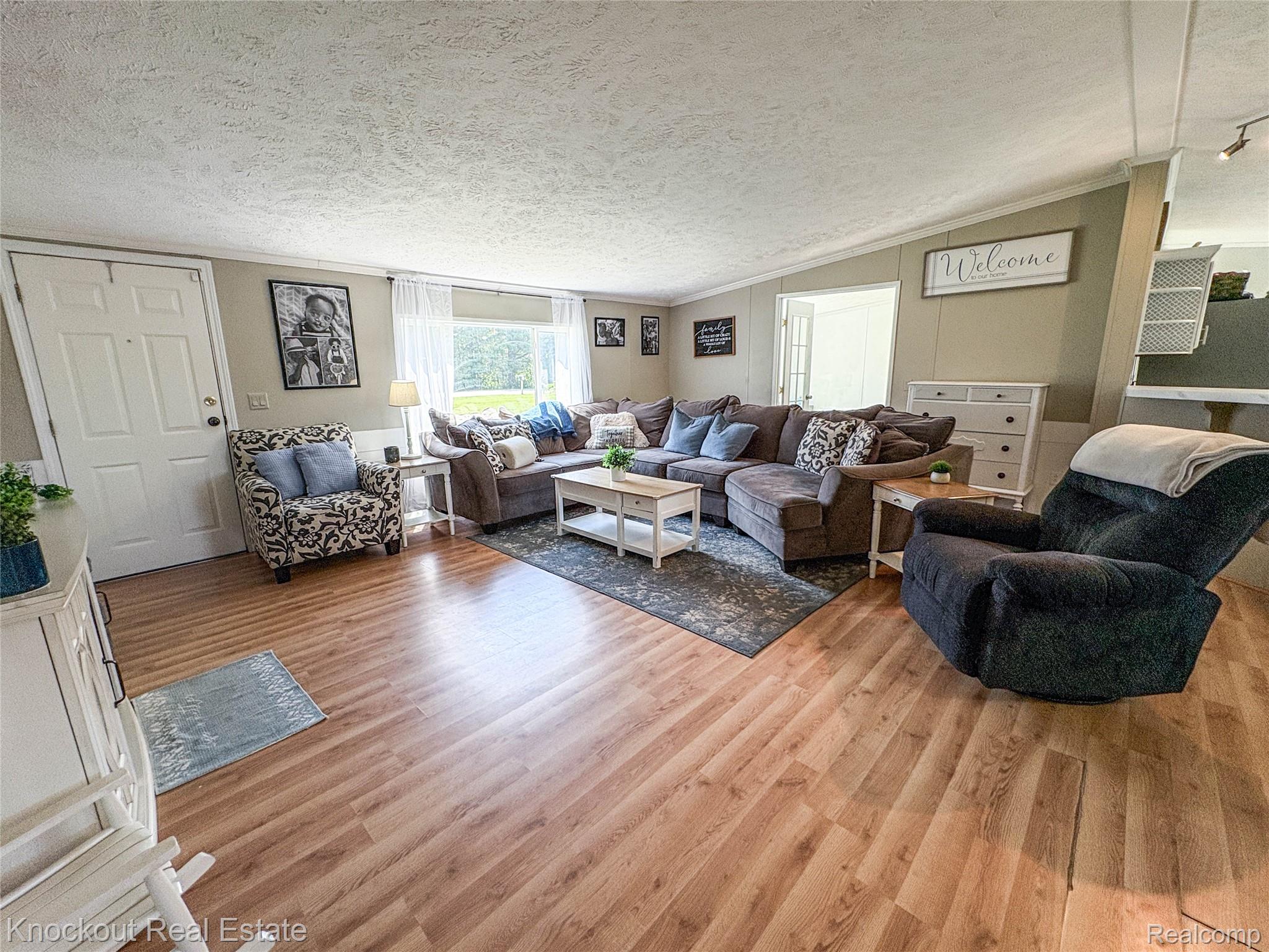 7760 Bell Road Birch Run, MI 48415 - Photo 5 of 68 Spacious living area featuring wood-finish flooring, a large window with natural light, and neutral wall tones