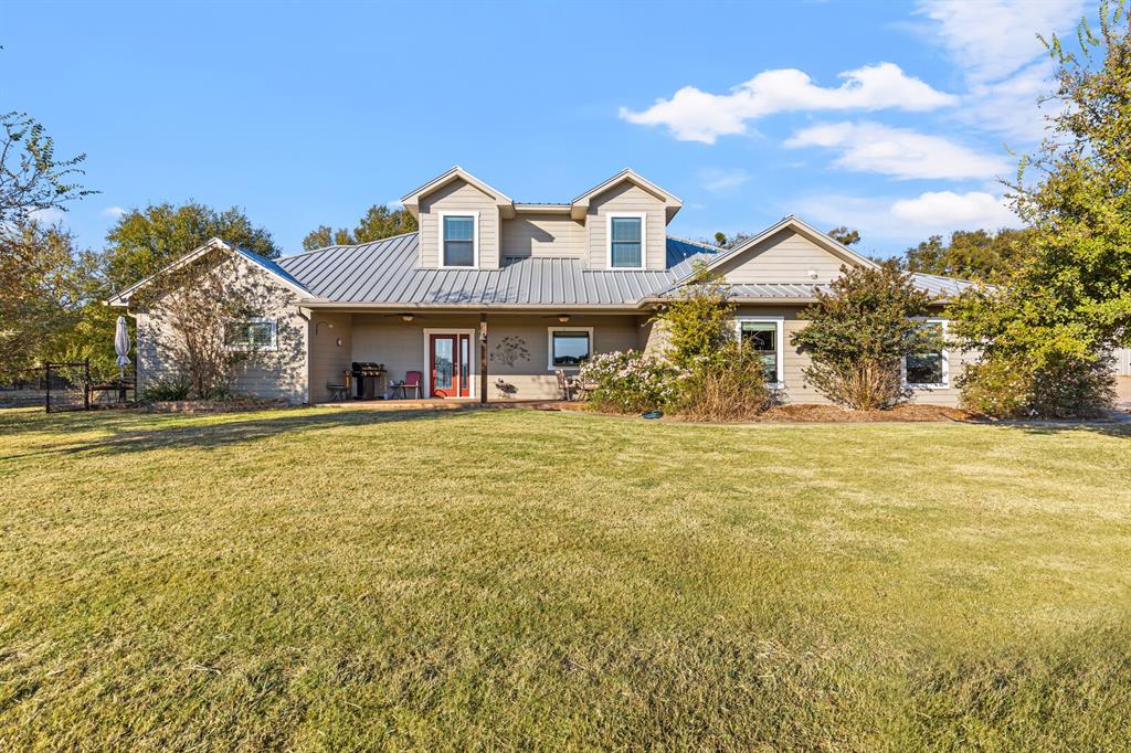 View of front of home featuring a metal roof and a front lawn