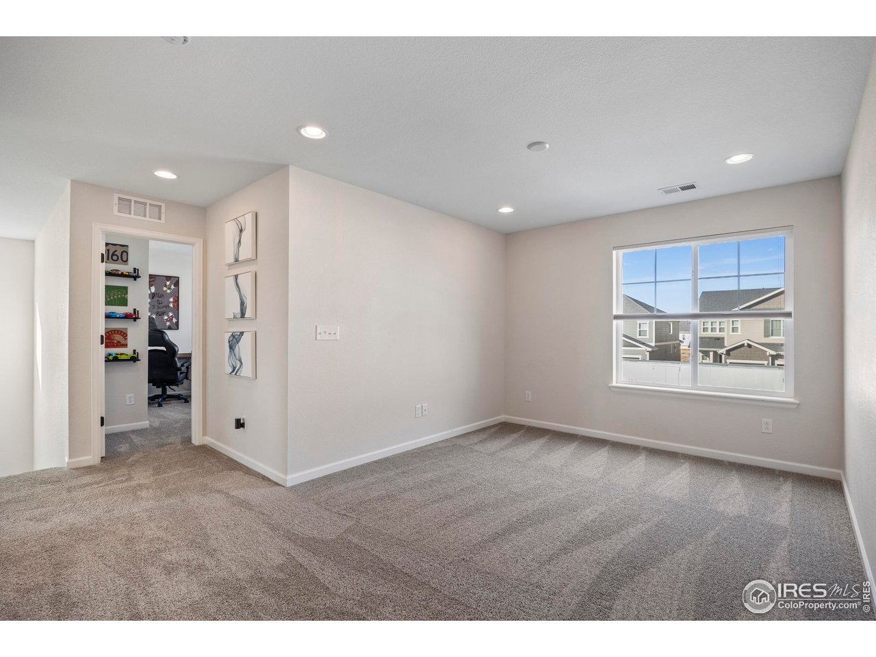951 Rustling Street Windsor, CO 80550 - Photo 21 of 47 a view of an empty room with wooden floor and a window