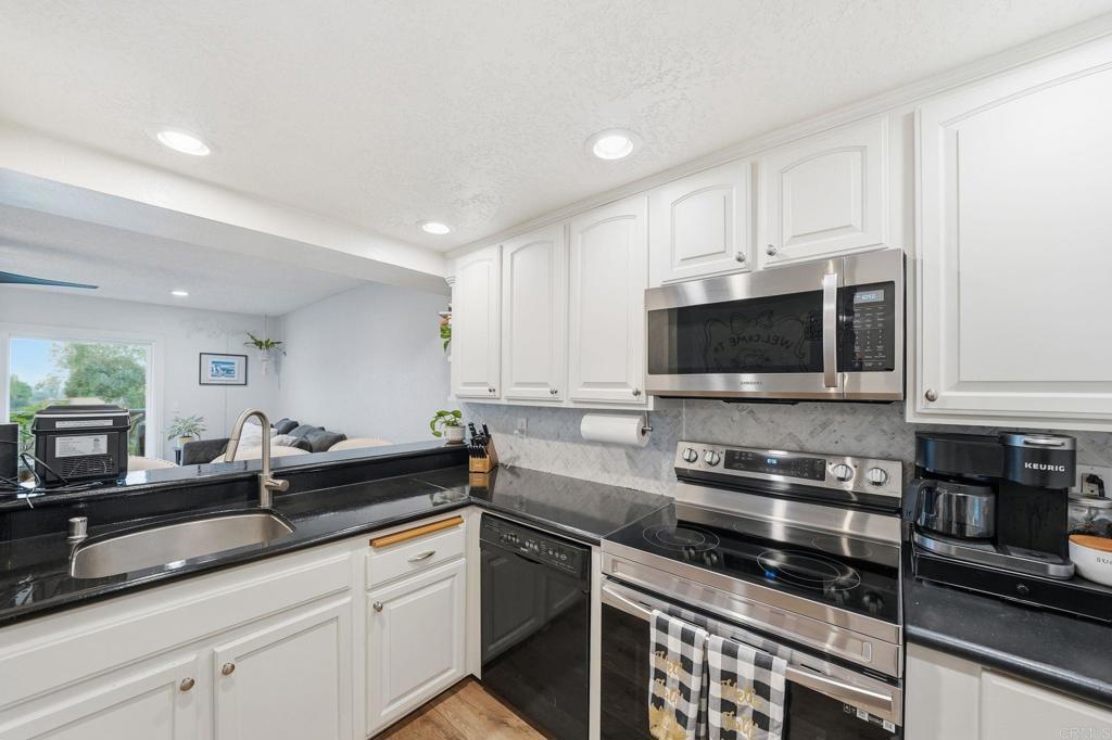 3711 Balboa Terrace, Unit B San Diego, CA 92117 - Photo 9 of 39 a kitchen with stainless steel appliances a sink a stove a microwave a sink and cabinets