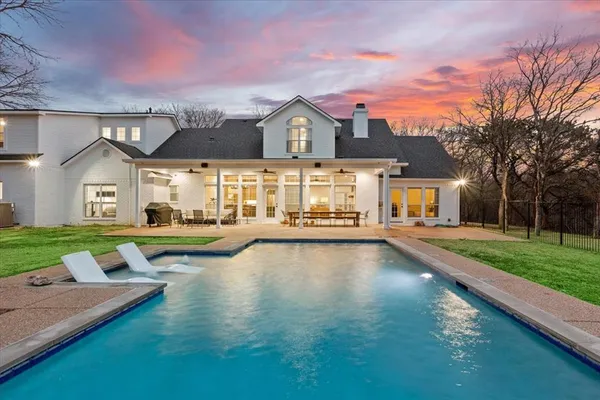 a view of a house with a swimming pool with a yard and a large tree