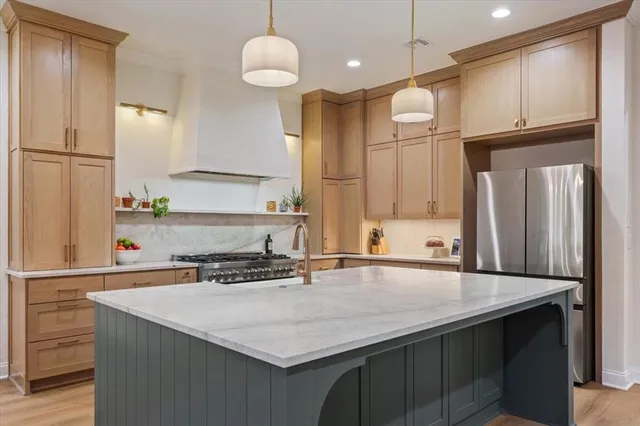 a kitchen with stainless steel appliances a sink a refrigerator a center island and cabinets