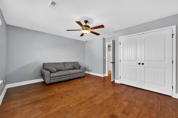 a view of an empty room with wooden floor and furniture