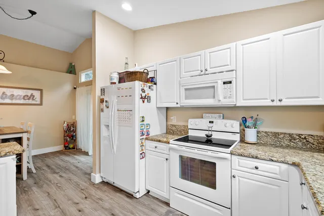 a kitchen with stainless steel appliances white cabinets and wooden floor