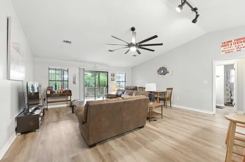 a living room with furniture and a dining table with kitchen appliances