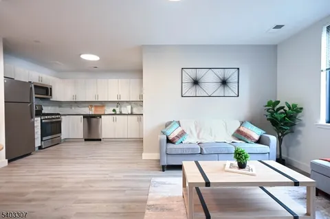 a living room with stainless steel appliances furniture and a kitchen view
