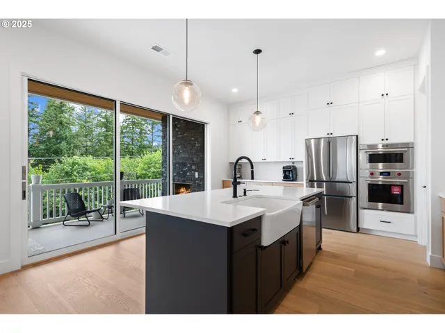 a open kitchen with stainless steel appliances granite countertop a sink a oven and a large window with wooden floors