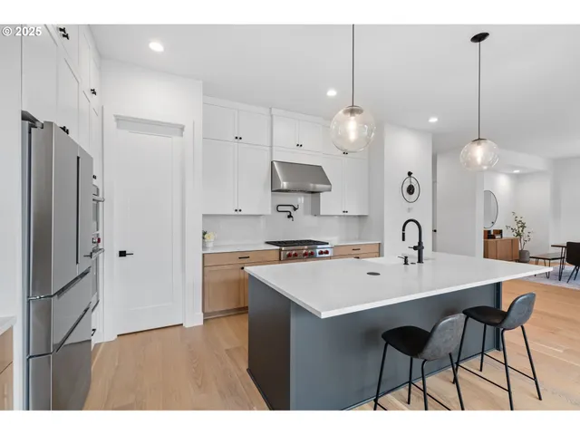 a kitchen with a sink a refrigerator a stove a kitchen island with chairs and wooden cabinets