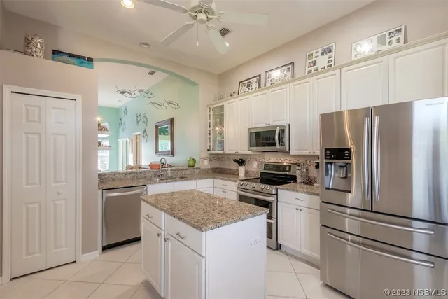 a kitchen with granite countertop a refrigerator oven a sink dishwasher and white cabinets with wooden floor