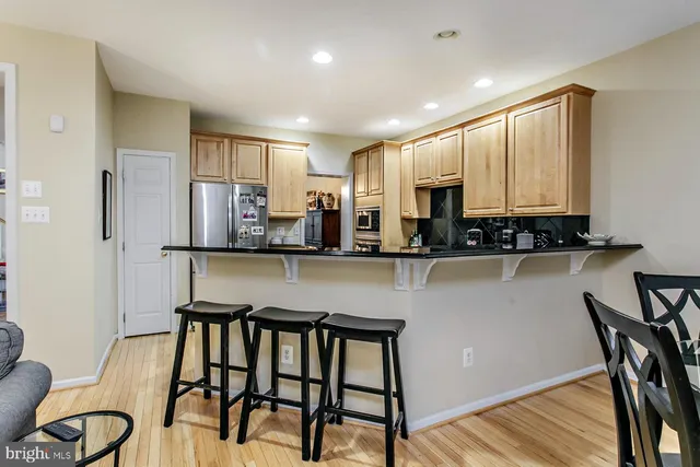 a kitchen with stainless steel appliances granite countertop table chairs sink and cabinets