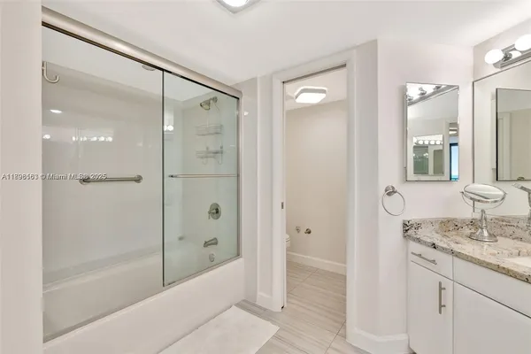 a bathroom with a shower sink vanity and mirror