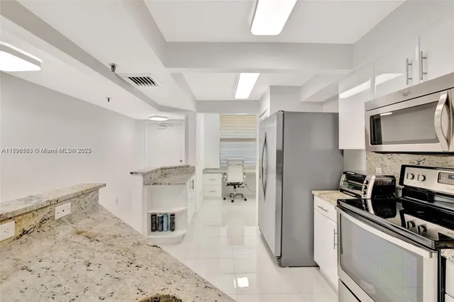 a kitchen with stainless steel appliances kitchen island granite countertop a refrigerator a stove and a sink with cabinets