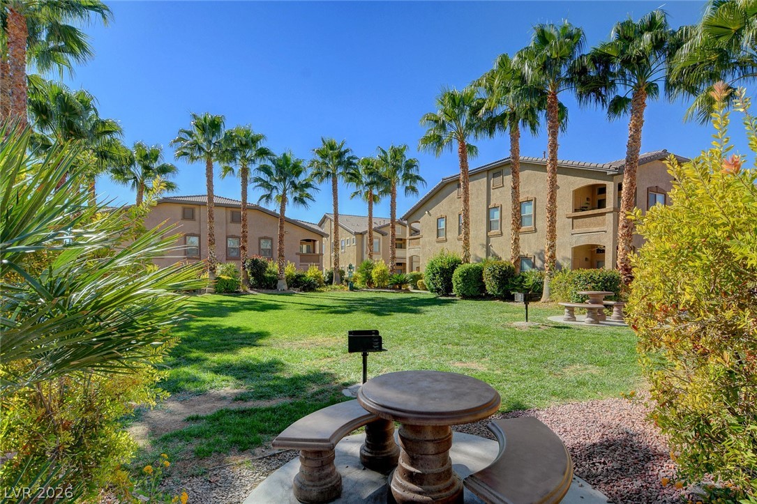 8985 South Durango Drive, Unit 2187 Las Vegas, NV 89113 - Photo 71 of 73 A verdant common area beckons with picnic tables and a built-in barbecue, framed by swaying palm trees.