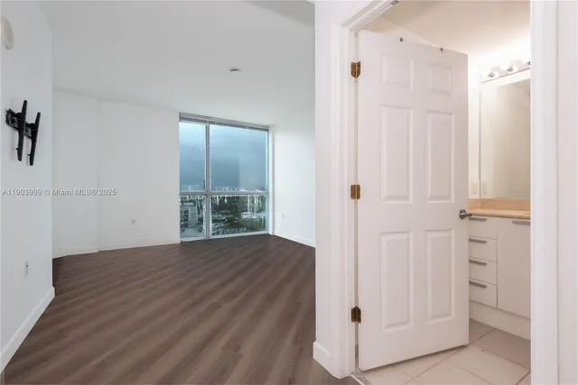 a view of a hallway with wooden floor and closet area
