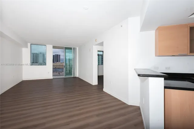 a view of an empty room with wooden floor and a window