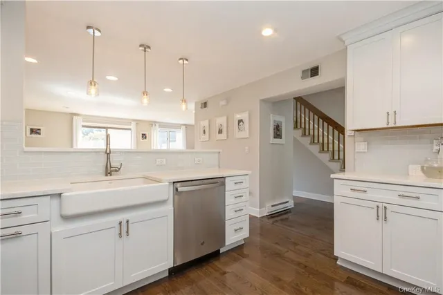 a kitchen with white cabinets appliances and wooden floor