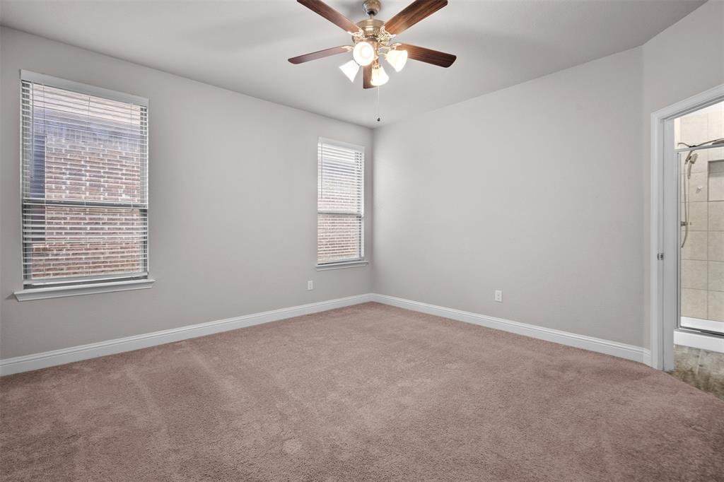 119 Happy Lane Red Oak, TX 75154 - Photo 20 of 37 Carpeted room featuring neutral wall paint, two windows with blinds, a ceiling fan with integrated lighting, and direct access to a tiled shower enclosure