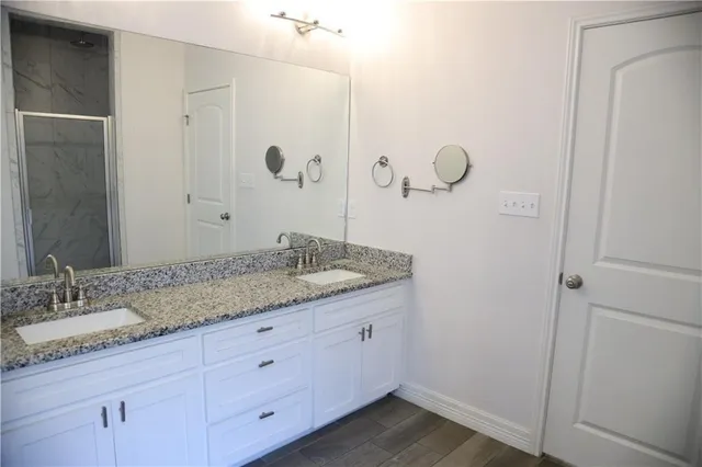 a bathroom with a granite countertop sink a mirror and a shower