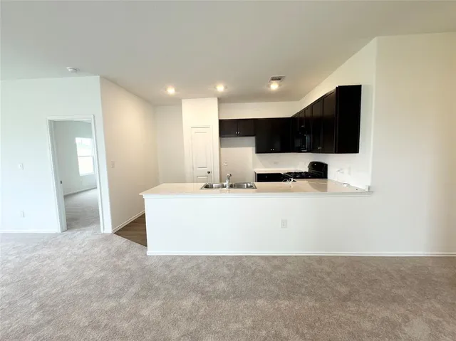 a view of kitchen with stainless steel appliances granite countertop a sink a stove and a refrigerator